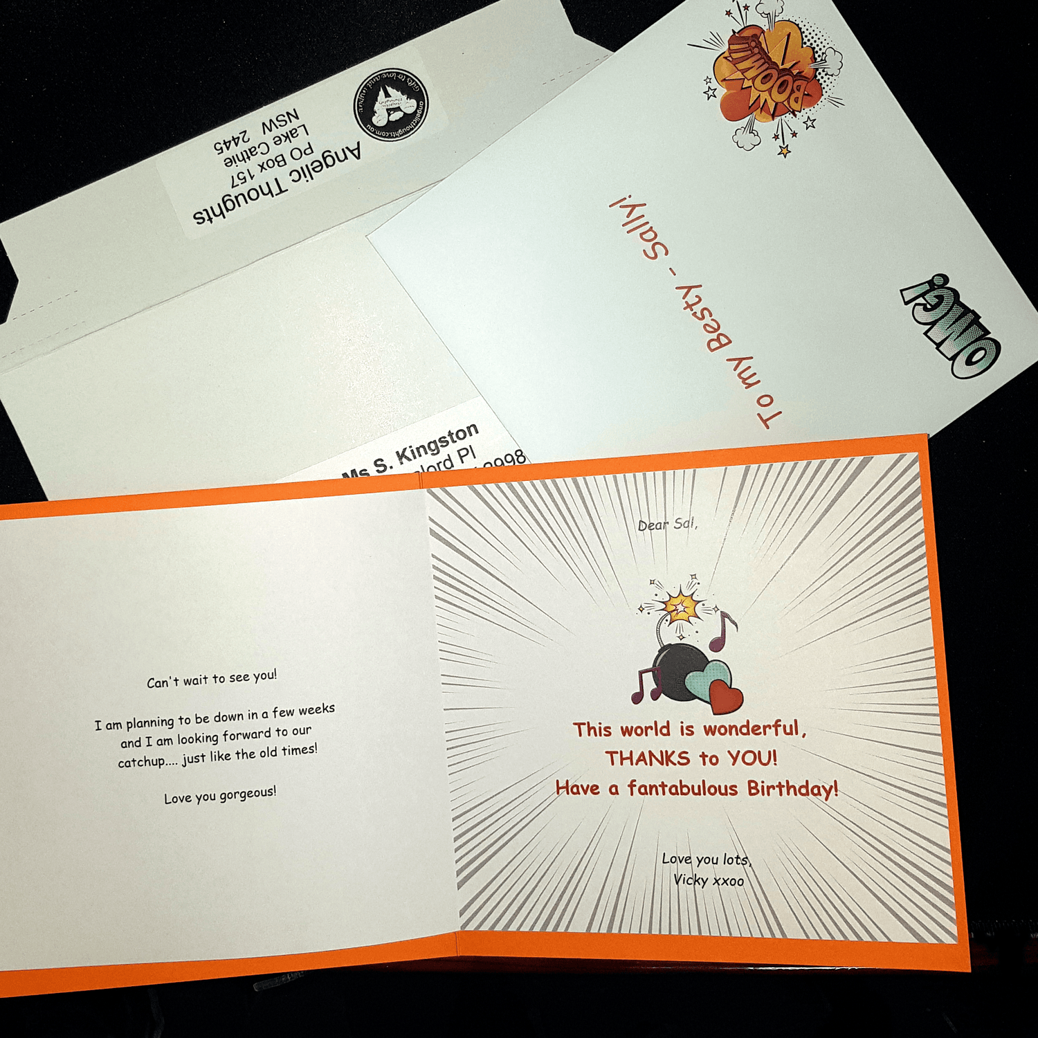 An open card which has been customised laying on an envelope and rigid mailer