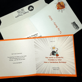 An open card which has been customised laying on an envelope and rigid mailer