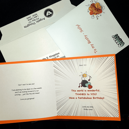 An open card which has been customised laying on an envelope and rigid mailer