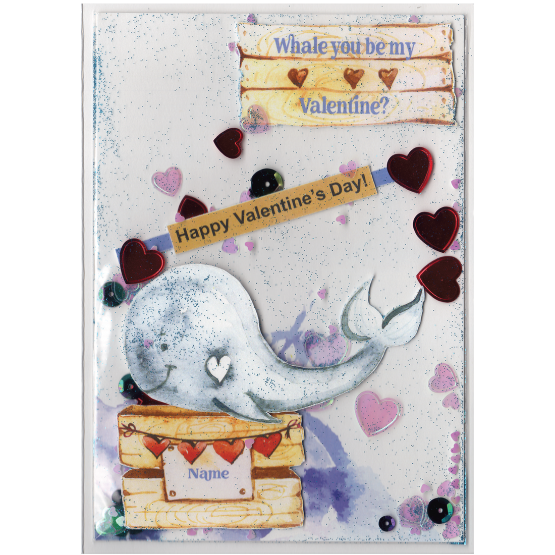 Handmade card featuring a raised cutout whale on a wooden box with heart banner and the customisable name of the recipient. It is fully enclosed in a shaker pocket with irridescent and red hearts of varying sizes and blue glitter.