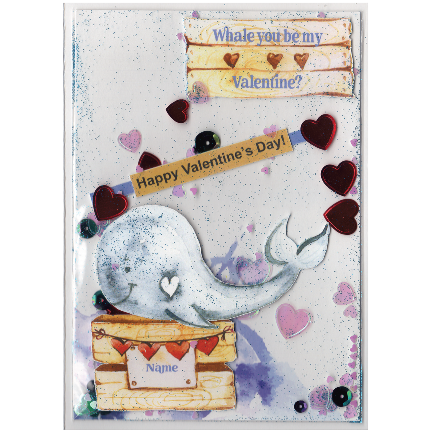 Handmade card featuring a raised cutout whale on a wooden box with heart banner and the customisable name of the recipient. It is fully enclosed in a shaker pocket with irridescent and red hearts of varying sizes and blue glitter.