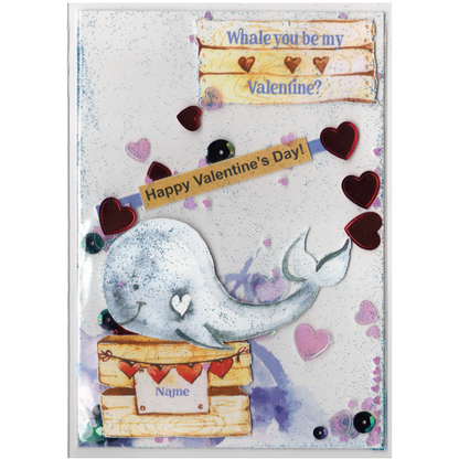 Handmade card featuring a raised cutout whale on a wooden box with heart banner and the customisable name of the recipient. It is fully enclosed in a shaker pocket with irridescent and red hearts of varying sizes and blue glitter.